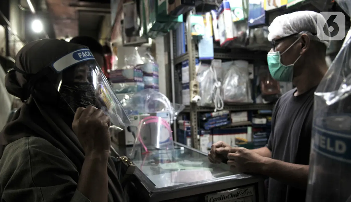 Pedagang alat pelindung wajah atau face shield melayani pembeli di salah satu kios Pasar Pramuka, Jakarta, Rabu (3/6/2020). Face shield di Pasar Pramuka dijual dengan harga mulai Rp 15 ribu hingga Rp 90 ribu per unit. (merdeka.com/Iqbal S. Nugroho)