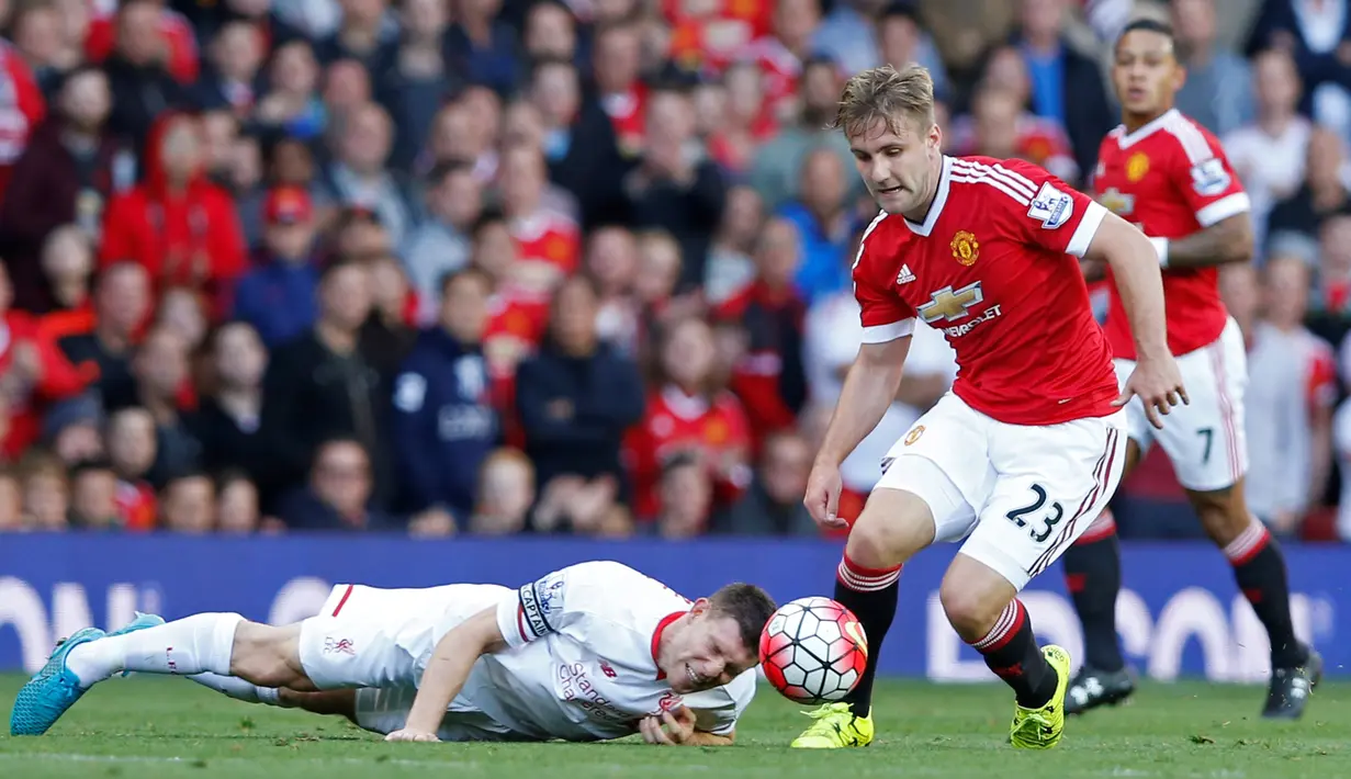 Pemain Liverpool, James Milner terjatuh saat berebut bola dengan pemain MU, Luke Shaw, di Stadion Old Trafford, Inggris. Sabtu (12/9/2015). (Action Images via Reuters/Carl Recine)