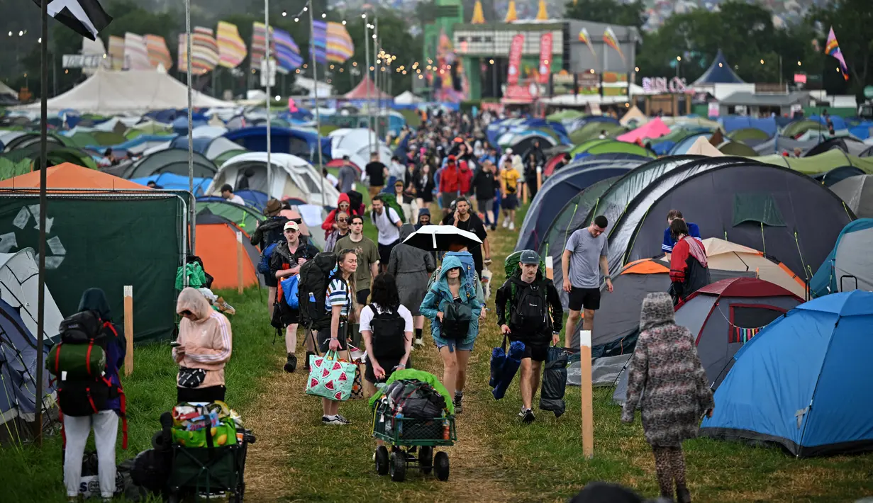 Pengunjung festival berjalan di tengah hujan melewati tenda pada hari pertama festival Glastonbury di desa Pilton, di Somerset, Inggris barat daya, pada 21 Juni 2023. (AFP/Oli Scarff)