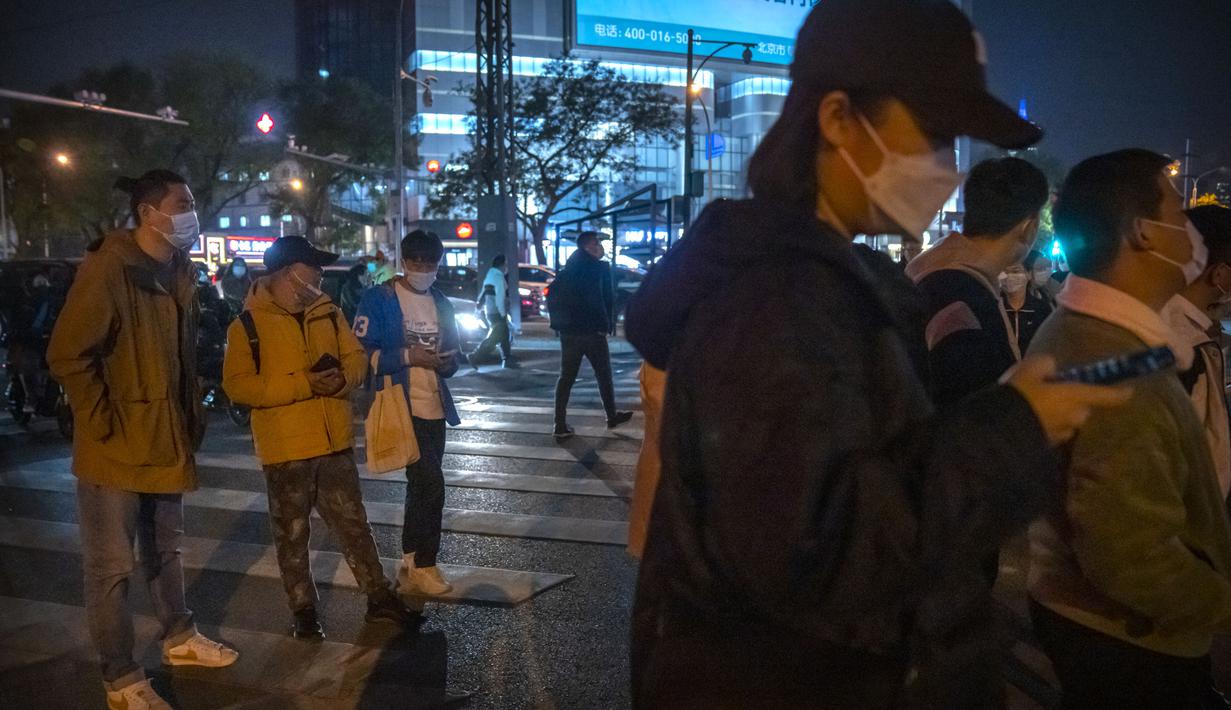 Komuter yang mengenakan masker menunggu di persimpangan di Beijing, Rabu (2/11/2022). Para pekerja iPhone Apple Inc meninggalkan pabrik karena lokasinya berada dalam zona industri Kota Zhengzhou yang sedang diberlakukan lockdown setelah adanya 64 laporan kasus virus corona di kawasan tersebut. (AP Photo/Mark Schiefelbein)