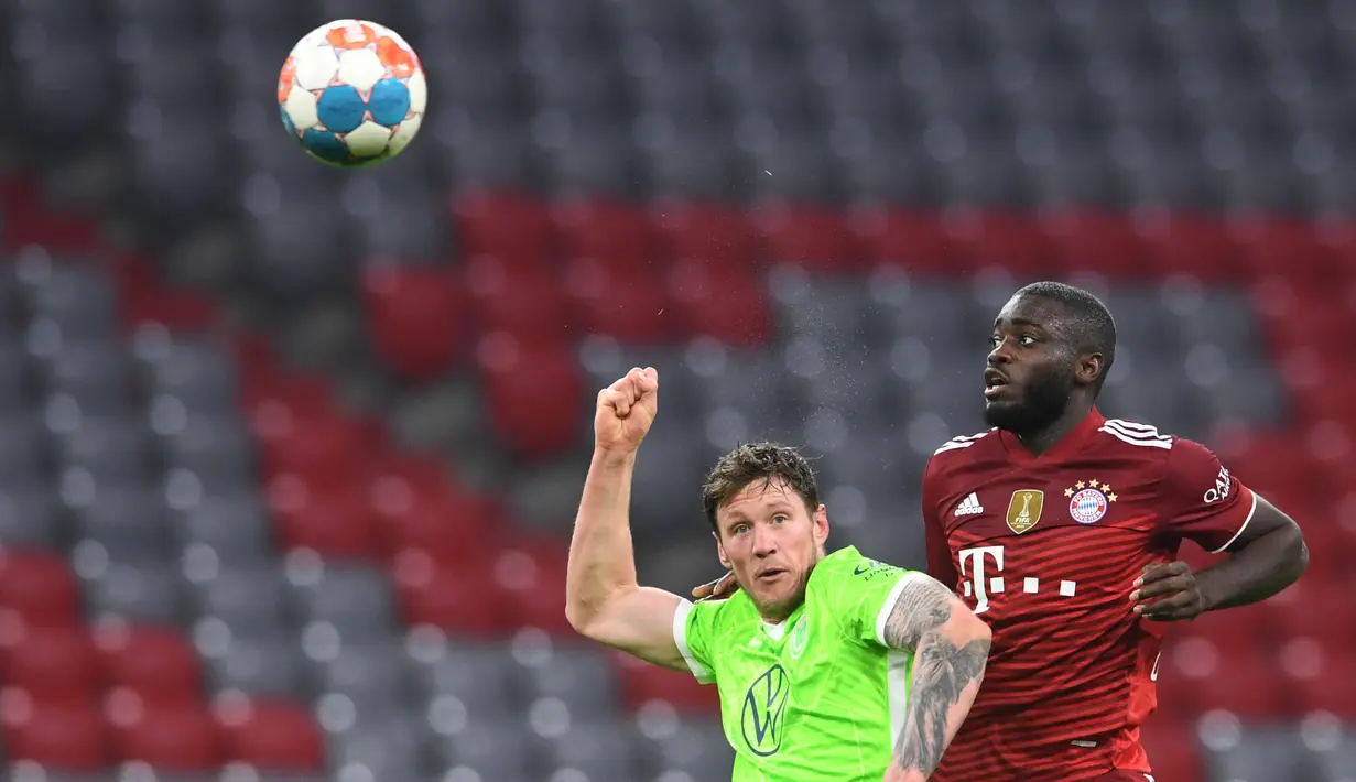 Penyerang VfL Wolfsburg Wout Weghorst (kiri) berebut bola dengan bek Bayern Munchen Dayot Upamecano pada pekan ke-17 Liga Jerman di Allianz Arena Sabtu (18/12/2021) dinihari WIB. Bayern mencukur Wolfsburg dengan skor 4-0. (Christof STACHE / AFP)