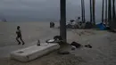 Seorang pria berlari melewati kasur ketika beberapa tunawisma berbaur di samping perkemahan mereka yang didirikan di sepanjang trotoar di lingkungan Venesia Los Angeles, Selasa (29/7/2021). Menjamurnya perkemahan tunawisma di Pantai Venice telah memicu protes dari penduduk. (AP Photo/Jae C.Hong)