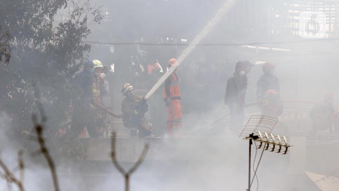 Petugas pemadam berusaha memadamkan api yang membakar pemukiman warga di kawasan Jalan Kebayoran Lama, Jakarta, Minggu (30/10/2022). Kebakaran terjadi persisi di belakang RS Permata Hijau di Jalan Raya Kebayoran Lama. Total ada 100 personel yang turun ke lokasi memadamkan api. (Liputan6.com/Helmi Fithriansyah)