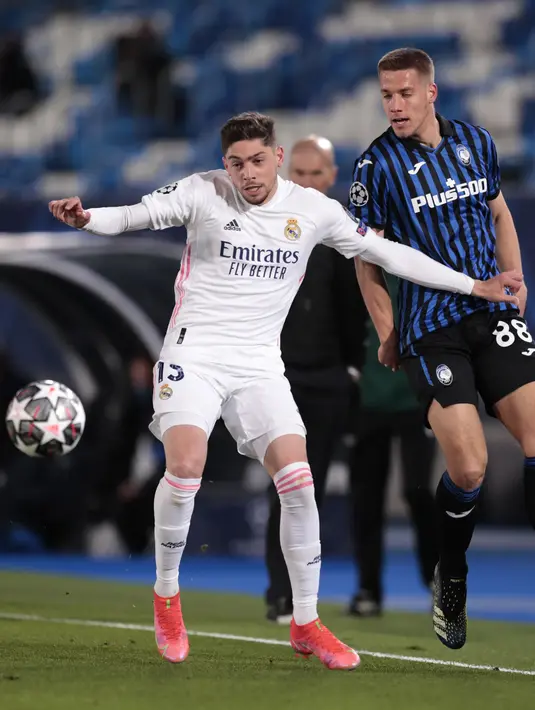 Gelandang Real Madrid, Federico Valverde berebut bola dengan gelandang Atalanta Mario Pasalic  pada leg kedua babak 16 besar Liga Champions di Estadio Alfredo di Stefano, Rabu (17/3/2021) dini hari WIB. Real Madrid menang 3-1 dan lolos ke perempat final dengan agregat 4-1. (AP Photo/Bernat Armangue)