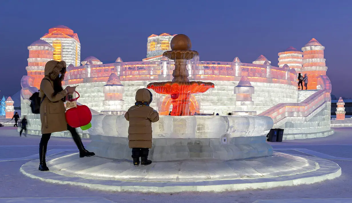 Pengunjung mengamati pahatan es yang dihiasi sorotan lampu warna-warni di Festival Dunia Es dan Salju Harbin, Harbin, Provinsi Heilongjiang, China, Selasa (5/1/2021). Festival yang berlangsung tahunan ini adalah festival salju dan es terbesar di dunia. (Chinatopix via AP)