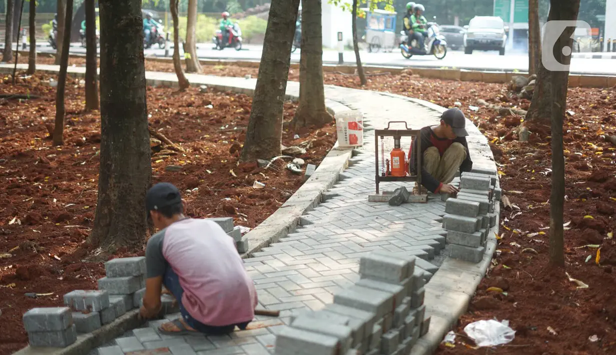 Pekerja menyelesaikan pembuatan jogging track di Taman Citra PPSU Srengseng Sawah, Jakarta, Rabu (4/12/2019). Jogging track tersebut dibuat guna meningkatkan kenyamanan bagi warga yang ingin beraktivitas di taman tersebut. (Liputan6.com/Immanuel Antonius)