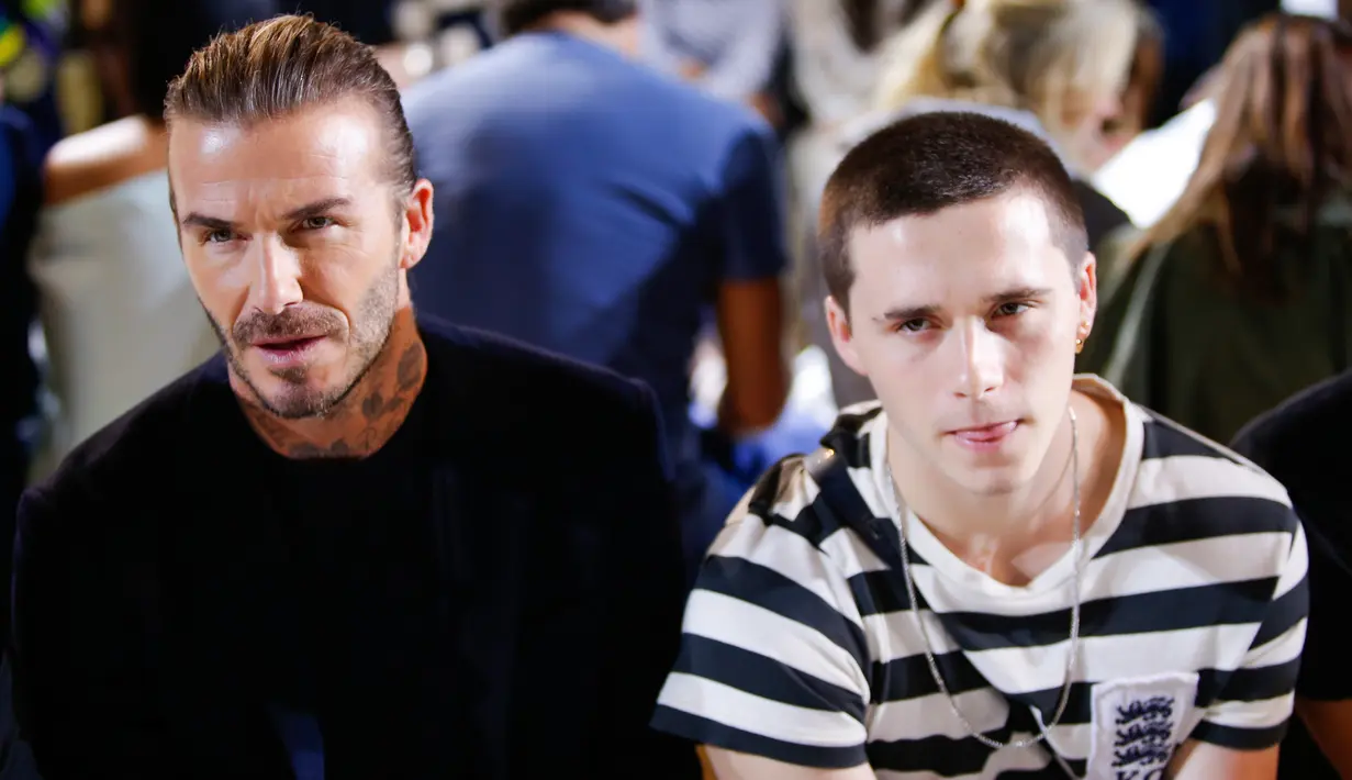 Mantan pesepakbola, David Beckham dan putranya Brooklyn tampak duduk di barisan depan fashion show koleksi musim panas 2018 Victoria Beckham dalam pagelaran New York fashion Week, Minggu (10/9). (EDUARDO MUNOZ ALVAREZ / AFP)