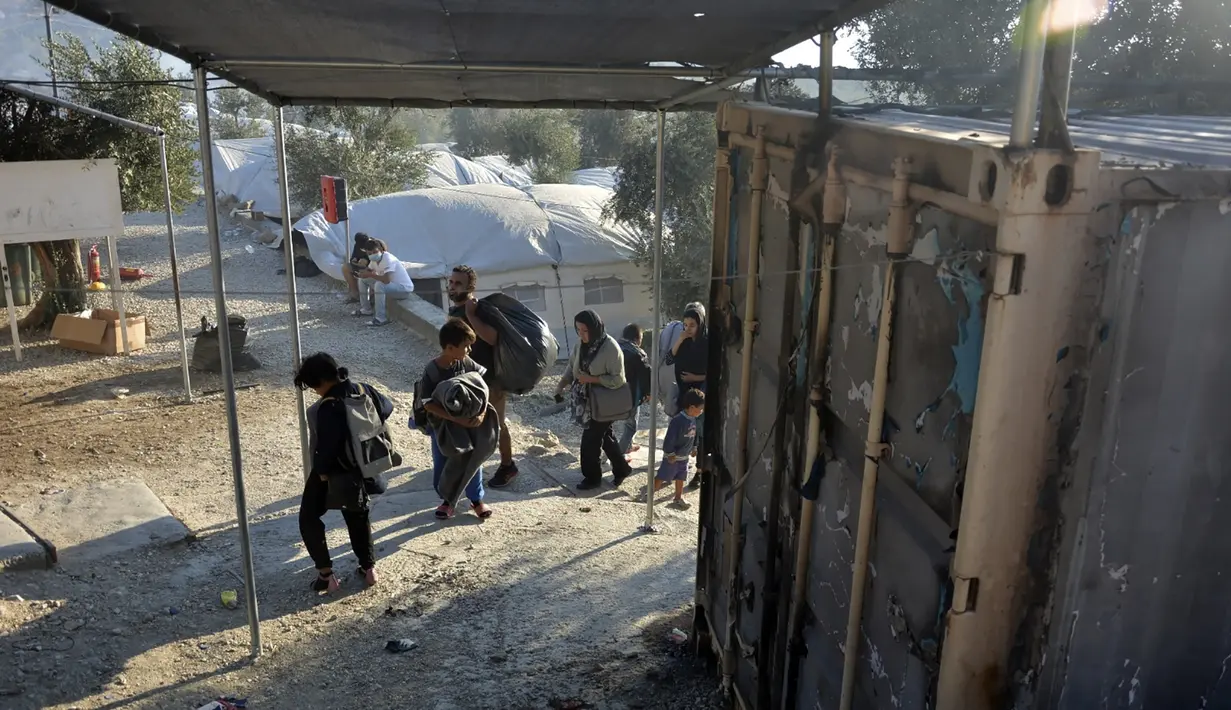 Migran berjalan di kamp pengungsi Moria saat terjadi kebakaran di pulau Lesbos di timur laut Aegean, Yunani, Rabu (9/9/2020). Otoritas kesehatan sebelumnya mengonfirmasi terdapat 35 kasus positif Covid-19 di kamp tersebut setelah melakukan pengujian sampel Covid-19 . (AP Photo/Panagiotis Balaskas)