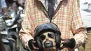 Seorang sukarelawan berpakaian seperti pengendara sepeda motor memegang kepala mockup dengan helm mengambil bagian dalam kampanye kesadaran keselamatan jalan dengan petugas polisi di Chennai (7/7/2021). (AFP/Arun Sankar)
