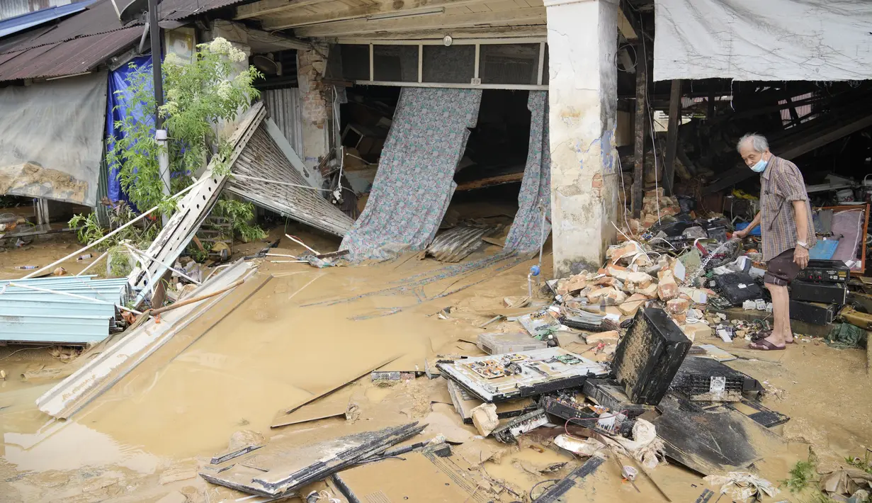 Seorang pria membersihkan toko mereka yang furniturnya rusak akibat terendam banjir di luar toko mereka di Hulu Langat, di luar Kuala Lumpur, Malaysia, Minggu (19/12/2021). Kuala Lumpur dan perkampungan sekitarnya dilanda banjir akibat hujan deras selama dua hari. (AP Photo/Vincent Thian)