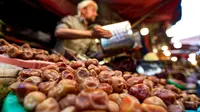 Seorang pedagang Yaman memperlihatkan kurma kering di sebuah pasar di kota tua Sanaa, Sabtu (11/5/2019). Buah kurma sangat identik saat bulan suci Ramadan, malah menjadi makanan wajib saat berbuka puasa. (Photo by Mohammed HUWAIS / AFP)