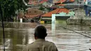 Warga menyaksikan luapan air kali Ciliwung yang menggenangi pemukiman di kawasan Rawajati, Jakarta, Selasa (8/3/2016). Akibat banjir kiriman dari Bogor, ratusan rumah di kawasan Rawajati terendam hingga kedalaman 120cm. (Liputan6.com/Helmi Fithriansyah)