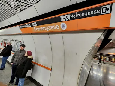 Para pelancong menunggu kereta bawah tanah U3 mereka di stasiun Herrengasse (Jalan Pria) yang ditutup dengan tanda sementara Frauengasse (Jalan Wanita) untuk merayakan Hari Perempuan Internasional di Wina, Austria, Rabu (8/3/2023). Dalam bahasa Inggris, ini berarti mengubah nama dari "Men's Lane" menjadi "Women's Lane". (JOE KLAMAR / AFP)