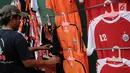 Pedagang merapikan atribut Persija di kawasan Senayan, Jakarta, Minggu (9/12). Pedagang memanfaatkan momen pertandingan Persija Jakarta yang akan bertanding melawan Mitra Kukar. (Liputan6.com/Faizal Fanani)