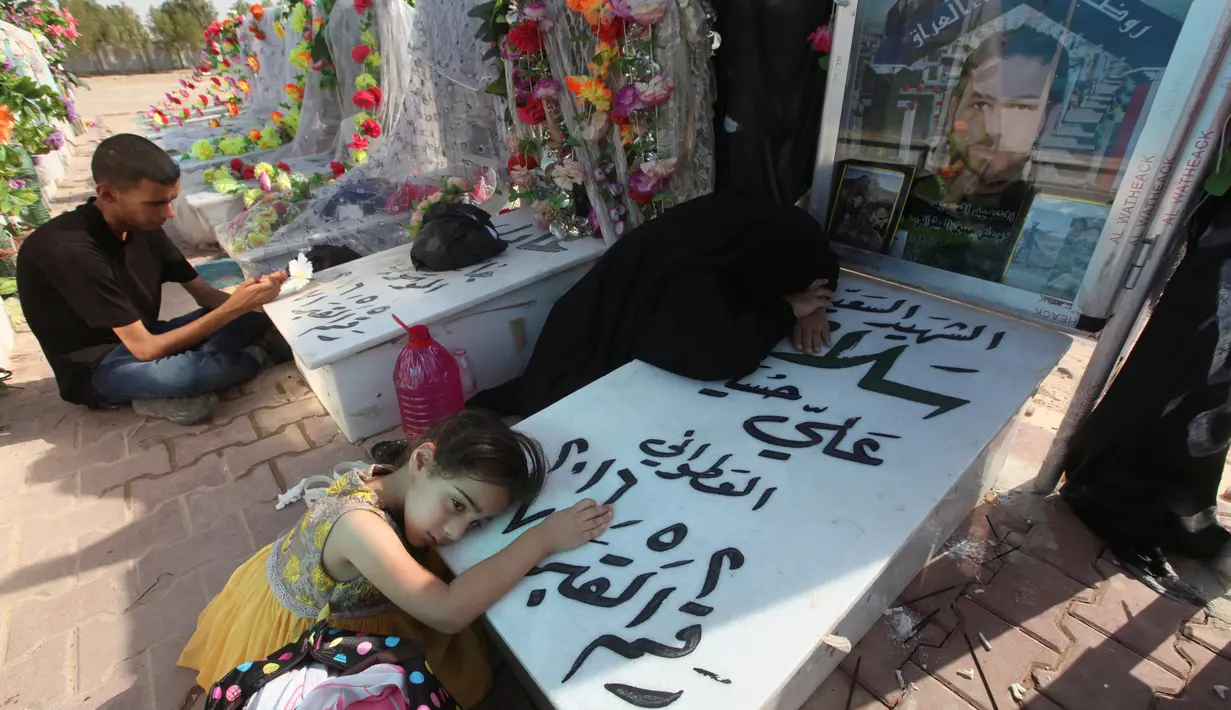 Keluarga mengunjungi makam kerabat mereka di pemakaman Wadi al-Salam, di Najaf, selatan Baghdad, Irak, 5 Agustus 2016. Sebagian besar masyarakat Irak meyakini banyak jasad raja, pangeran dan sultan bersemayam di sana. (REUTERS/Alaa Al-Marjani)