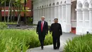 Momen ketika Presiden AS Donald Trump (kiri) dengan Pemimpin Korea Utara Kim Jong-un berjalan di taman Hotel Capella, Pulau Sentosa, Singapura, Selasa (12/6). Trump dan Kim optimis bahwa KTT akan sukses. (Anthony Wallace/Pool/AFP)