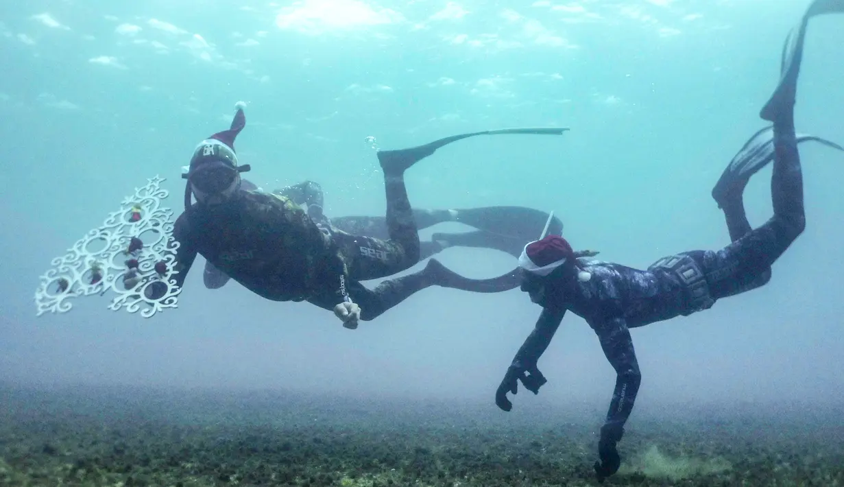 Penyelam berjuang untuk menempatkan pohon Natal di dasar laut lepas pantai Tripoli, Lebanon, Selasa (18/12). Hal ini dilakukan untuk menyambut Natal. (IBRAHIM CHALHOUB/AFP)