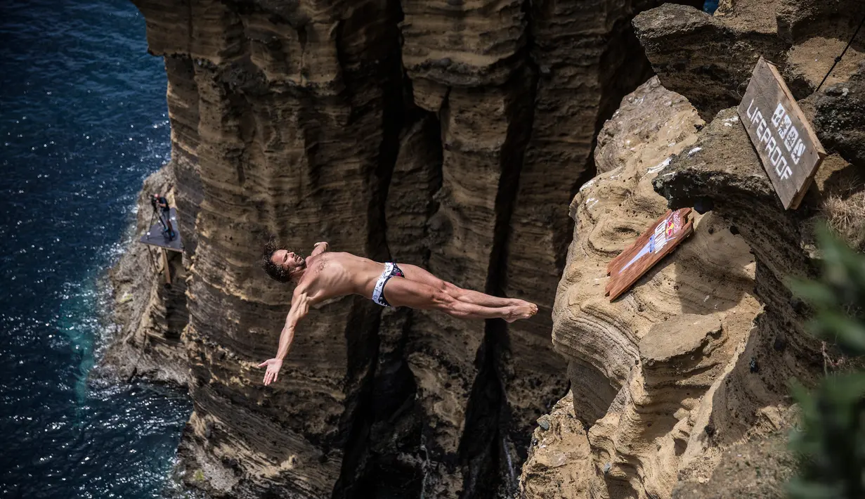 Peserta asal Bulgaria, Todor Spasov, melakukan lompatan setinggi 27 meter dari tebing Islet Franca do Campo dalam kompetisi Red Bull Cliff Diving World Series di Sao Miguel, Portugal, 7 Juli 2017. (Romina Amato/Red Bull Content Pool via AP Images)