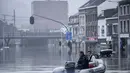 Warga menggunakan rakit karet di tengah banjir setelah Sungai Meuse jebol saat banjir besar di Liege, Belgia, Kamis (15/7/2021). Banyak orang hilang saat air naik dan menyebabkan beberapa rumah runtuh. (AP Photo/Valentin Bianchi)