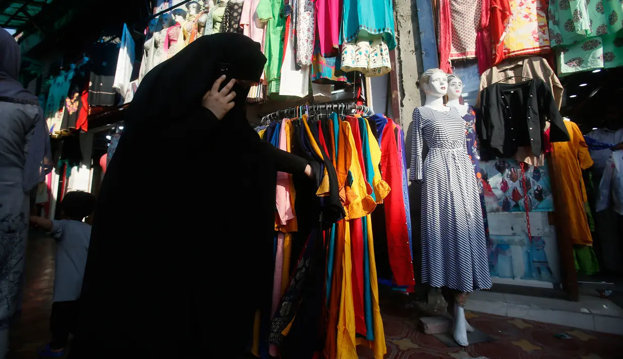 Seorang wanita muslim Kashmir mencari pakaian sebelum Idul Fitri di Srinagar, Kashmir yang dikuasai India (2/6/2019). Idul Fitri, menandai berakhirnya bulan puasa Ramadan. (AP Photo/Mukhtar Khan)