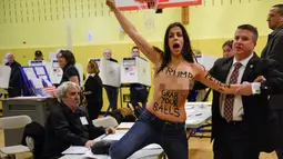 Pihak keamanan berusaha mengusir wanita bertelanjang dada yang melakukan demonstrasi di TPS Pilpres AS 59, New York, Selasa (8/11). Kedua wanita setengah bugil itu melakukan aksinya di TPS tempat Donald Trump akan memberikan suara. (REUTERS/Darren Ornitz)