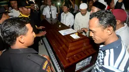 Keluarga berdiri di dekat peti jenazah Yudhistira Febbi Arianto, co pilot pesawat Aviastar yang tiba di sebuah masjid dekat Bandara Ngurah rai, Bali, Kamis (8/10). Pesawat Aviastar jatuh dan menewaskan 3 kru dan 7 penumpang. (AFP PHOTO/SONNY TUMBELAKA)