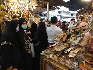 Sejumlah wanita mencari sandal saat berbelanja di sebuah pasar di Lahore, Pakistan (4/5/2021). Di tengah pandemi virus corona Covid-19, sejumlah warga memadati area pasar tersebut menjelang hari Idul Fitri. (AFP/Arif Ali)