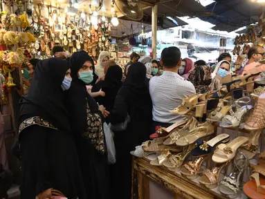 Sejumlah wanita mencari sandal saat berbelanja di sebuah pasar di Lahore, Pakistan (4/5/2021). Di tengah pandemi virus corona Covid-19, sejumlah warga memadati area pasar tersebut menjelang hari Idul Fitri. (AFP/Arif Ali)