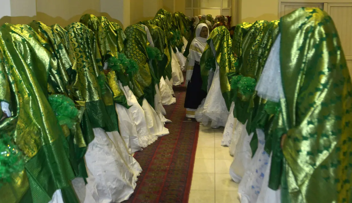Pengantin wanita berdiri dalam aula pernikahan saat mereka menunggu dimulainya upacara pernikahan massal di Kabul, Afghanistan, 13 Juni 2022. Upacara pernikahan dihadiri ratusan tamu dan pejuang Taliban yang membawa senjata. (Sahel ARMAN/AFP)
