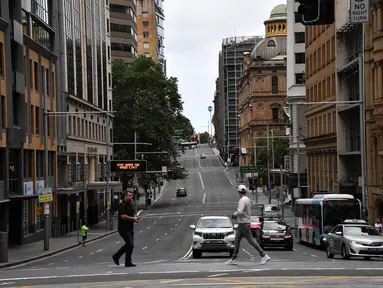Pejalan kaki melintasi jalan yang biasanya padat dengan lalu lintas di kawasan pusat bisnis di Sydney, Rabu (30/12/2020). Pihak berwenang berupaya menekan klaster kasus virus corona Covid-19 yang terus bertambah di kota terpadat di Australia tersebut. (Saeed KHAN / AFP)