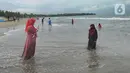 Wisatawan yang mengenakan masker menikmati suasana Pantai Anyer di Cilegon, Banten, Minggu (25/10/2020). Akhir pekan dimanfaatkan warga Jakarta dan sekitarnya untuk berwisata dengan tetap menerapkan protokol kesehatan Covid-19. (merdeka.com/Arie Basuki)