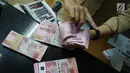 Teller menunjukkan mata uang rupiah di penukaran uang di Jakarta, Rabu (10/7/2019). Nilai tukar rupiah terhadap dolar Amerika Serikat (AS) ditutup stagnan di perdagangan pasar spot hari ini di angka Rp 14.125. (Liputan6.com/Angga Yuniar)