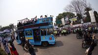 Masyarakat dan bobotoh menyambut pemain Persib diatas Bus Bandung Tour on Bus (Bandros) dalam Pawai Persib Juara Piala Presiden saat start dari Kota Baru Parahyangan, Bandung, Minggu (25/10/2015). (Bola.com/Nick Hanoatubun)
