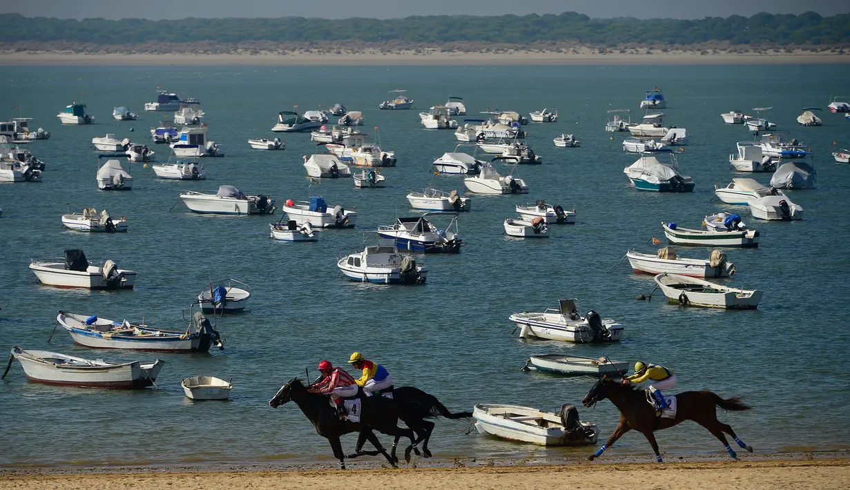 Peserta memacu kudanya saat mengikuti lomba pacuan kuda pantai tahunan di Sanlucar de Barrameda, dekat Cadiz, Spanyol (17/8). Pacuan kuda ini bermula dari para nelayan yang berlomba mengangkut tangkapan mereka melalui pantai. (AFP Photo/Cristina Quicler)
