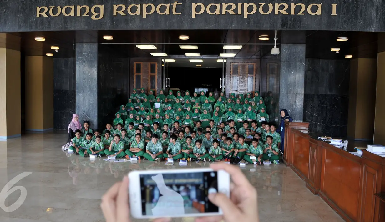 Siswa SD Al-Azhar Kebayoran Lama berfoto bersama usai kunjungan di depan ruang rapat paripurna 1 Gedung MPR/DPR RI, Jakarta, Kamis (5/11). Kunjungan itu dalam rangka study tour dan pemahaman materi pelajaran tentang trias politica. (Liputan6/Johan Tallo)