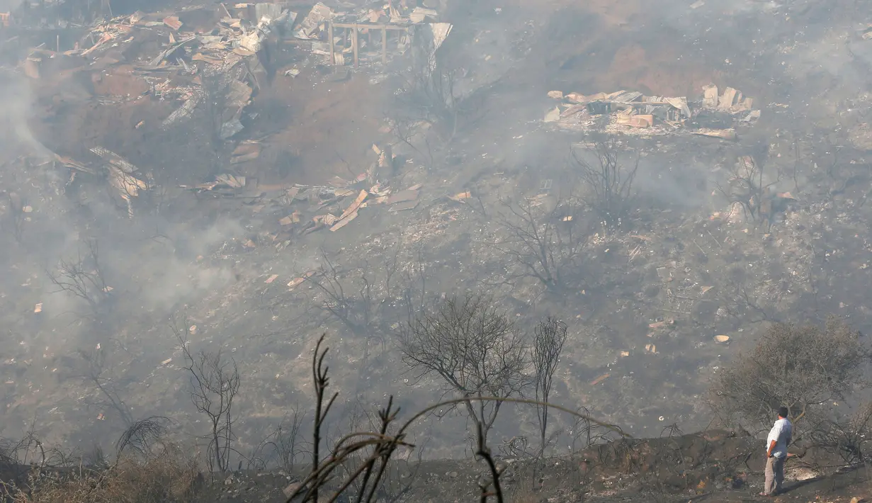 Seorang warga melihat sisa-sisa kebakaran besar yang melanda kota pantai Valparaiso di Chile, Senin (2/1). Otoritas setempat menyebut, angin kencang dan suhu udara yang tinggi turut memicu semakin meluasnya kebakaran ini. (REUTERS/Rodrigo Garrido)