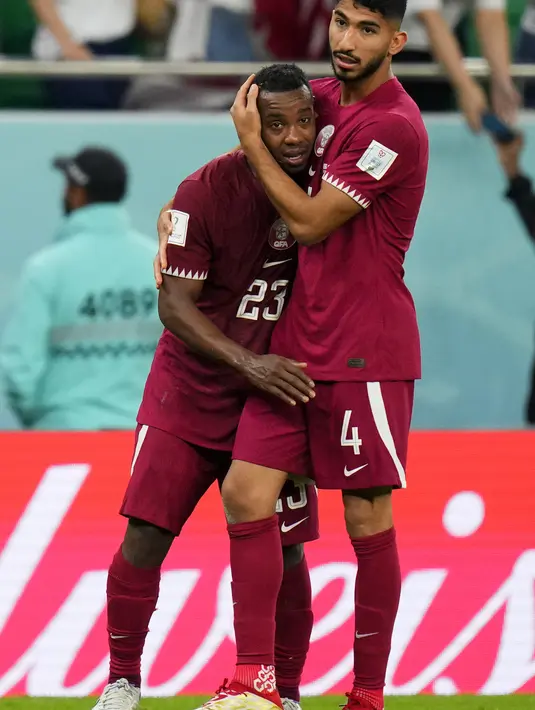 Gelandang Qatar, Mohammed Waad memeluk rekan setimnya Assim Madibo setelah kalah 1-3 dari Senegal dalam pertandingan grup A Piala Dunia di Stadion Al Thumama di Doha, Qatar, Jumat, 25 November 2022. Hasil ini membuat Qatar bernasib sama seperti Afrika Selatan pada 2010, yang juga terhenti di fase grup. (AP Photo/Petr Josek)