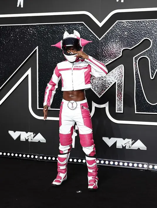 Lil Nas X muncul dengan busana pembalap berwarna pink dan putih, lengkap dengan helm raksasa dengan telinga berbentuk kerucut. [@mtv].