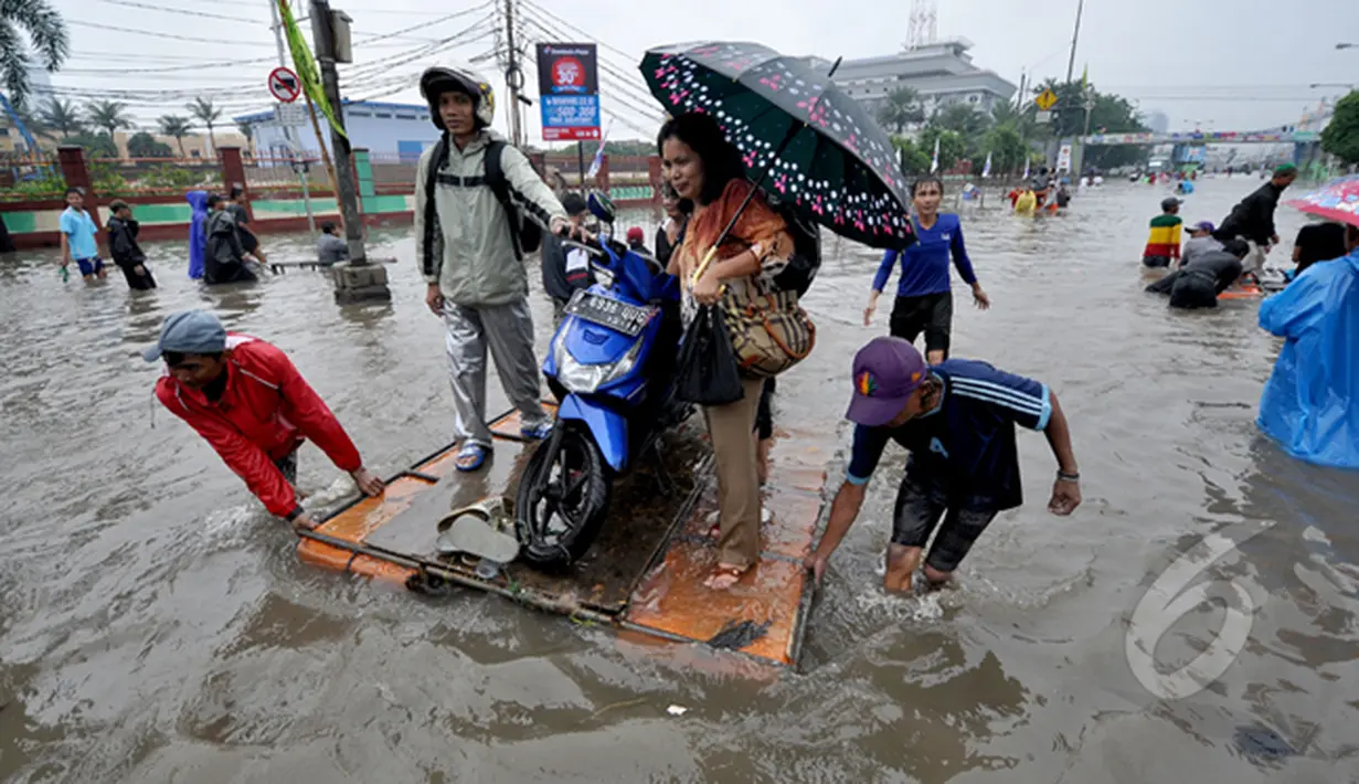 Pengendara motor saat menggunakan jasa gerobak untuk melintasi banjir di Jalan Gunung Sahari, Jakarta, Senin (6/2/2015). Jasa gerobak Mematok harga Rp. 30 ribu untuk membawa motor sedangkan untuk per orang hanya Rp. 10 ribu. (Liputan6.com/Faizal Fanani)