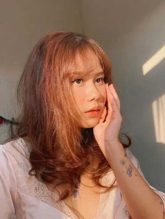 Gaya rambut poni tipis ala cewek Korea ini sukses menyempurnakan penampilan penyanyi Nadin Amizah. (Instagram/cakecaine).