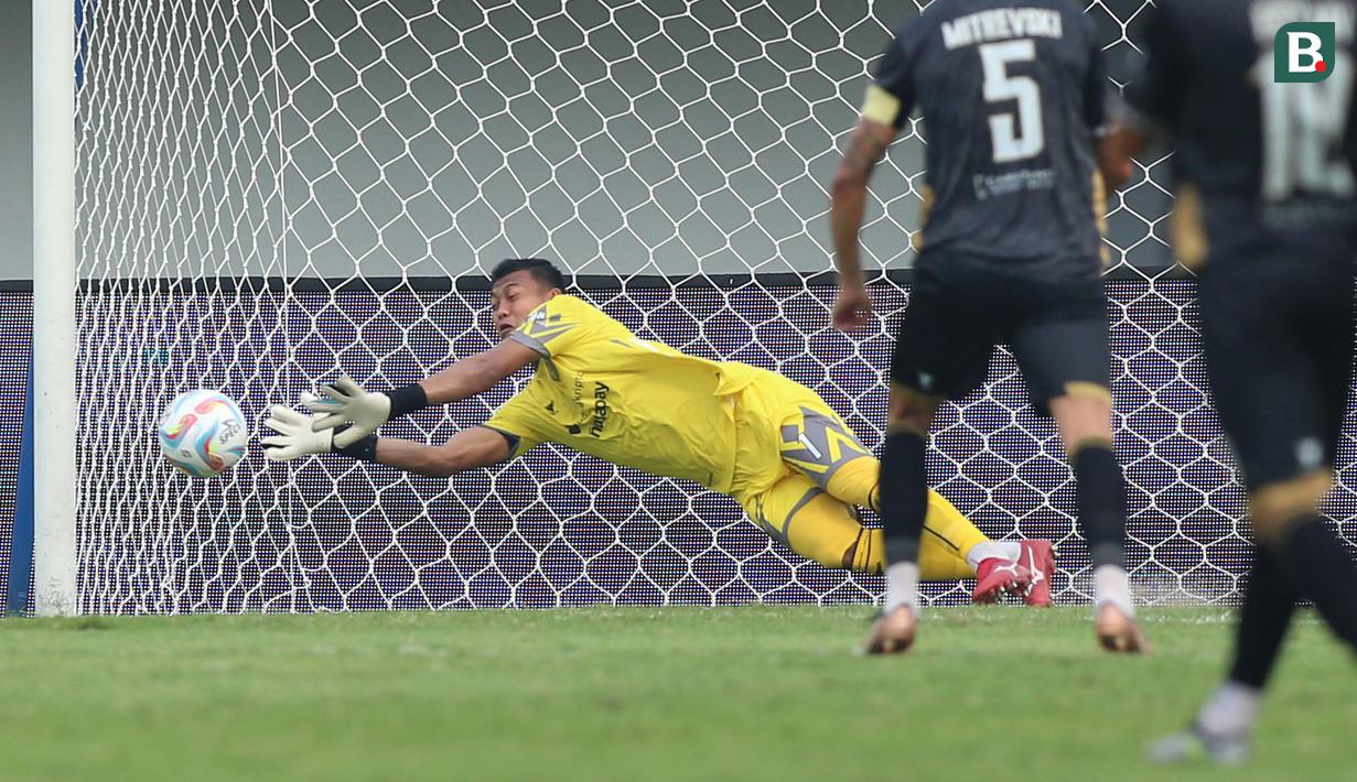 Kiper Dewa United FC, M Natshir Fadhil Mahbuby berusaha menghalau bola tendangan pemain Arema FC pada laga pekan pertama BRI Liga 1 2023/2024 antara Dewa United melawan Arema FC di Stadion Indomilk, Tangerang, Minggu (2/7/2023). (Bola.com/Bagaskara Lazuardi)