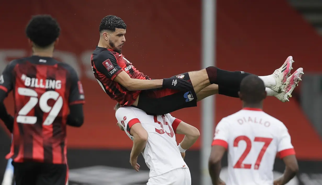 Striker Bournemouth, Dominic Solanke (atas) mendarat di atas punggung bek Southampton, Jan Bednarek saat perebutan bola dalam laga perempatfinal Piala FA 2020/2021 di Vitality Stadium, Bournemouth, Sabtu (20/3/2021). Bournemouth kalah 0-3 dari Southampton. (AP/Kirsty Wigglesworth)