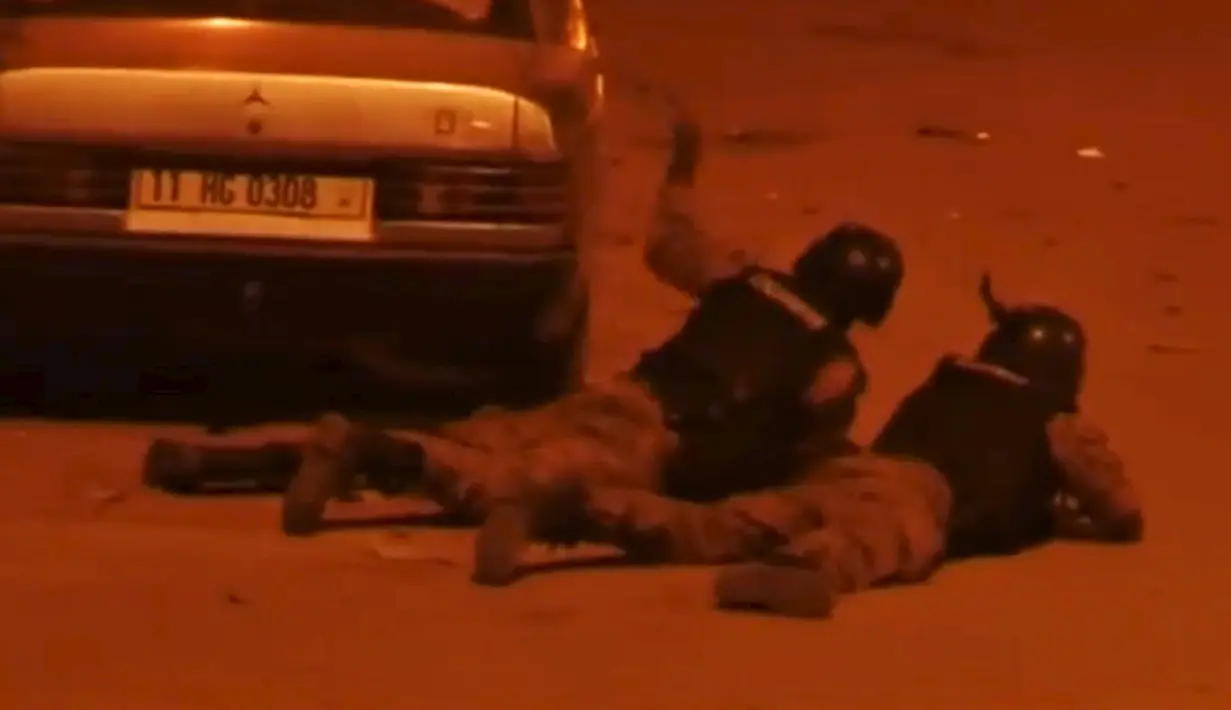 Petugas keamanan saat bersembunyi dibalik sebuah mobil saat terjadi penyanderaan yang dilakukan suatu kelompok radikal di Splendid, Ouagadougou, Burkina Faso, Jumat (15/1). (REUTERS / Reuters TV)