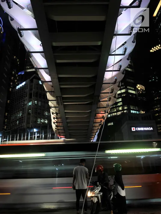 Warga menunggu kendaraan di bawah jembatan penyeberangan orang (JPO) Gelora Bung Karno (GBK), Jakarta, Senin (25/2). JPO GBK ini rencananya akan diresmikan oleh Gubenur Anies Baswedan pada Maret mendatang. (Merdeka.com/Iqbal S Nugroho)