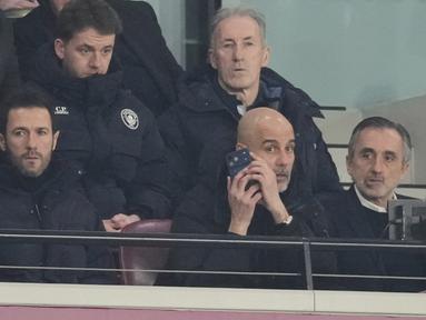 Pelatih Manchester City, Pep Guardiola, memberikan arahan melalui telpon dari tribun penonton saat anak asuhnya bermain imbang 1-1 melawan West Ham United pada pekan ke-30 Premier League 2025/2026 di London Stadium pada Minggu (15/3/2026). (AP Photo/Dave Shopland)