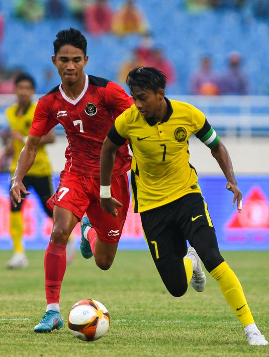 <p>Gelandang Timnas Malaysia U-23, Muhammad Mukhairi Ajmal bin Mahadi membawa bola dari kejaran gelandang Indonesia, Marselino Fedinan dalam pertandingan perebutan medali perunggu SEA Games 2021 di Stadion My Dinh, Minggu (22/5/2022). Indonesia ditahan imbang 1-1 dan menang 4-3 di adu penalti. (AFP/Tang Chhin Sothy)</p>