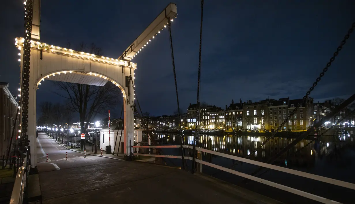 Sebuah jembatan yang sepi terlihat selama jam malam di pusat kota Amsterdam, Sabtu (23/1/2021). Belanda memasuki fase terberat dari pembatasan anti-virus Corona hingga saat ini. (AP Photo/ Peter Dejong)