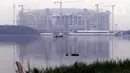 Warga memancing menggunakan perahu di Waduk Cincin yang berlatar pembangunan Jakarta International Stadium (JIS), Sabtu (19/6/2021). Pembangunan JIS sudah memasuki tahap pemasangan rangka atap dengan bentang mencapai 269 meter dan ditarget selesai Desember 2021. (Liputan6.com/Helmi Fithriansyah)