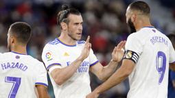Los Blancos membuka kedudukan terlebih dahulu lewat gol cepat Gareth Bale (kiri) ketika babak pertama baru berjalan lima menit. Bale sukses menuntaskan umpan Benzema meski dirinya dikawal oleh dua pemain. Papan skor berubah menjadi 1-0 atas keunggulan Real Madrid. (Foto: AP/Alberto Saiz)