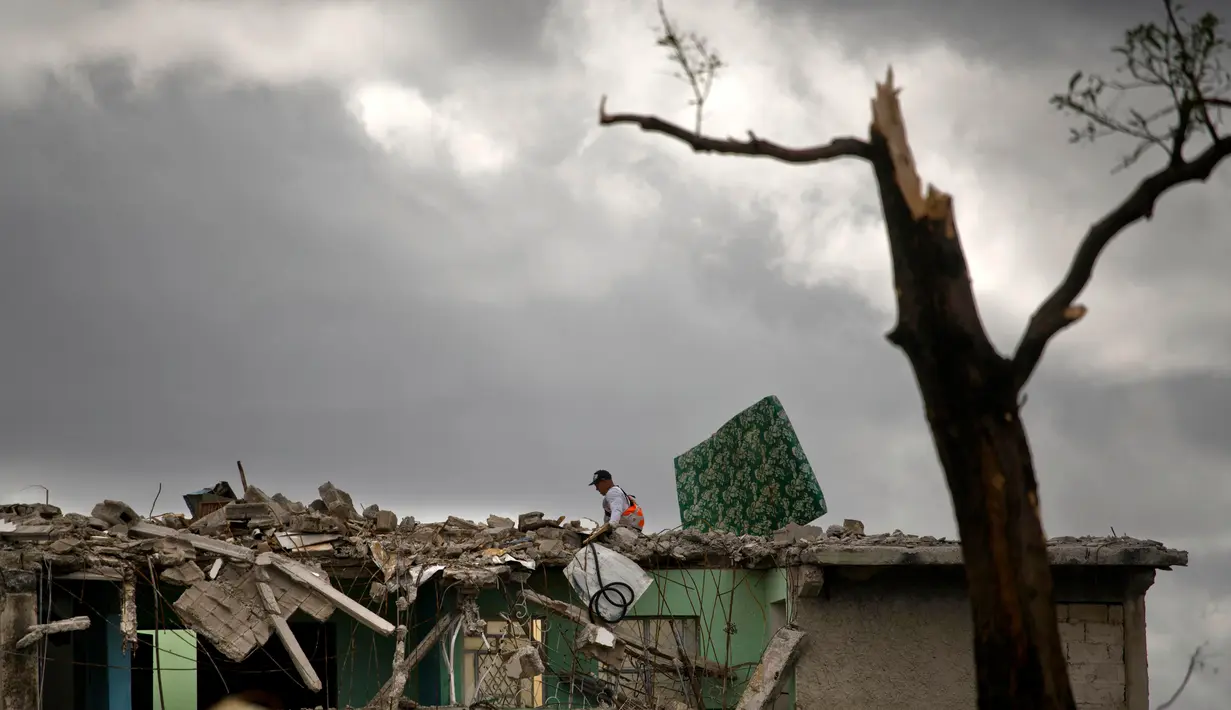 Seorang pria mencari barang miliknya di sebuah bangunan yang hancur dihantam badai tornado di Regla, Kuba (28/1). Hantaman tornado mengakibatkan rumah-rumah hancur berantakan, mobil bergelimpangan hingga pepohonan tumbang. (AP Photo/Ramon Espinosa)